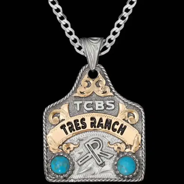 "Show off your Ranch pride with the Tux Cow Tag Necklace! Crafted on a hand-engraved, German Silver base with a natural finish. It's detailed with a German Silver rope edge, a Jeweler's Bronze banner and cubic zirconia stones with your choice of colo